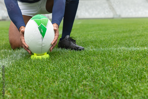 Foto African American male rugby player placing rugby ball on a stand in stadium