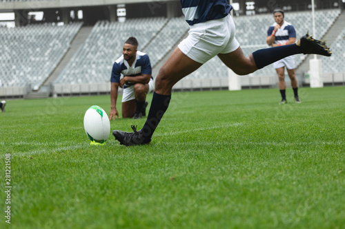 Fototapeta Naklejka Na Ścianę i Meble -  African American male rugby player kicking rugby ball in stadium