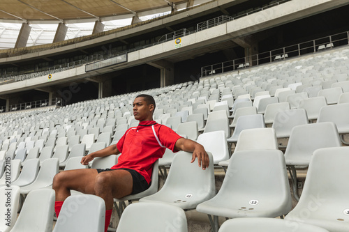 Thoughtful African American male rugby player sitting alone in stadium