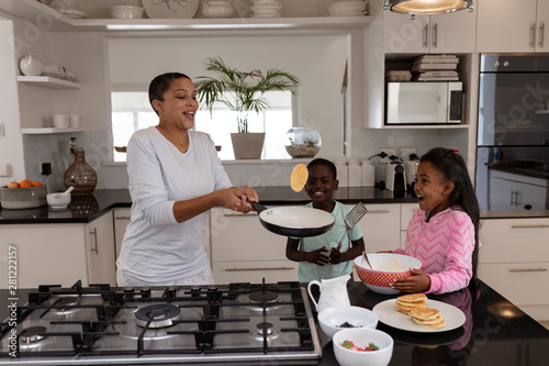 Slika na platnu Mother and children preparing food on a worktop in kitchen