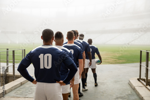 Diverse male rugby players standing at the entrance of stadium in a row for match