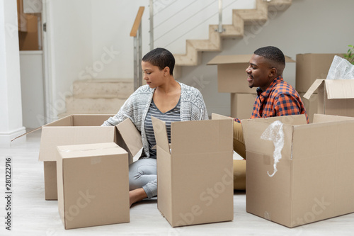 Couple unpacking cardboard boxes in living room