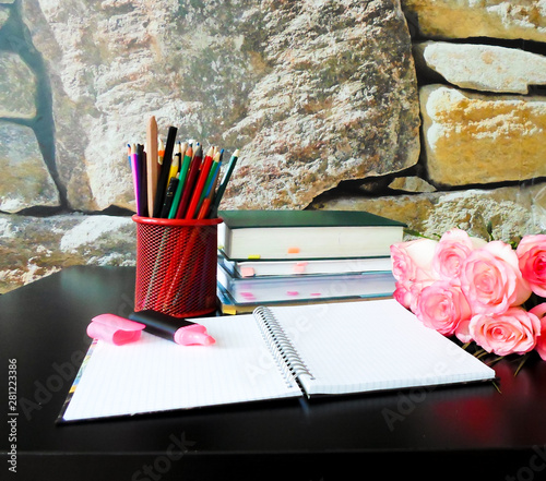 September 1 concept. Books, flowers, pencils on a black table and a white notebook with pink markers. Back to school photo