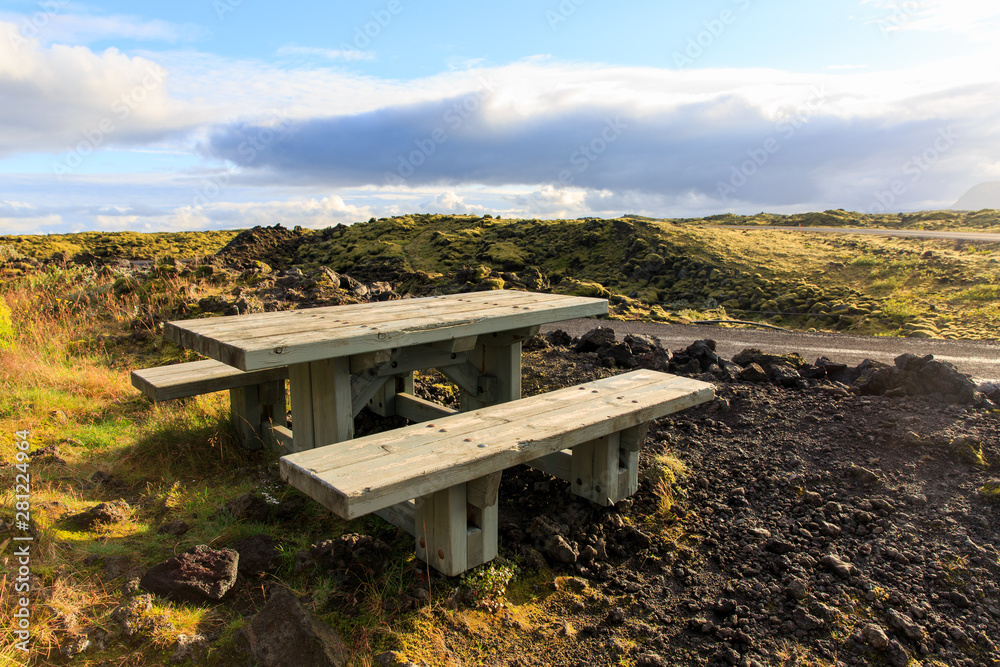 Empty wooden picnic table at sunset. Stone landscape, Iceland.