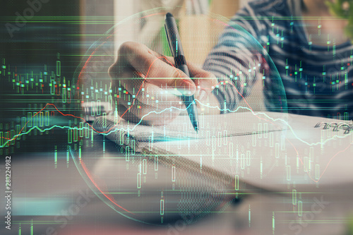 Financial forex graph drawn over hands taking notes background. Concept of research. Double exposure