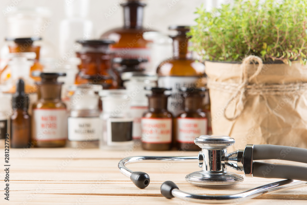 Alternative medicine concept medicine in bottles, medicinal herbs and stethoscope on a wooden table Alternative medicine concept medicine in bottles, medicinal herbs and stethoscope on a wooden table