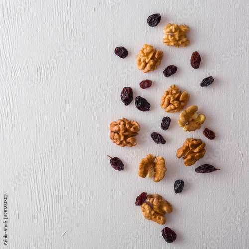A variety of peeled walnuts and raisins on a white wooden background. View from above. Plenty of space for text.