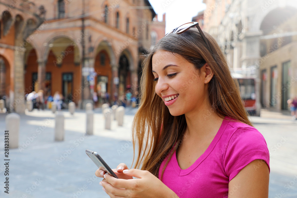 Fototapeta premium Portrait of smiling woman using smart phone in old medieval town
