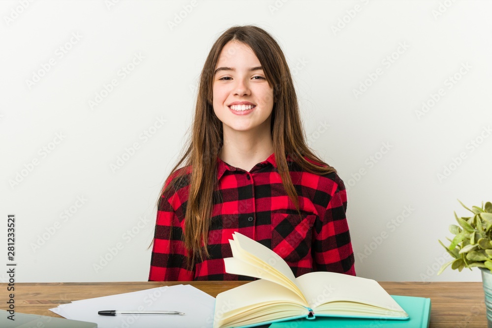 Young teenager going back to her routine doing homeworks laughs and closes eyes, feels relaxed and happy. Young teenager going back to her routine doing homeworks laughs and closes eyes, feels relaxed and happy.