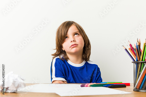 Photos Little boy painting and doing homeworks on his desk tired of a repetitive task