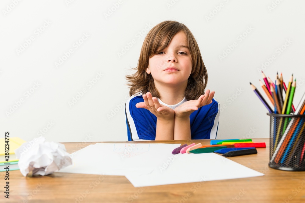 Little boy painting and doing homeworks on his desk folding lips and holding palms to send air kiss. Little boy painting and doing homeworks on his desk folding lips and holding palms to send air kiss.