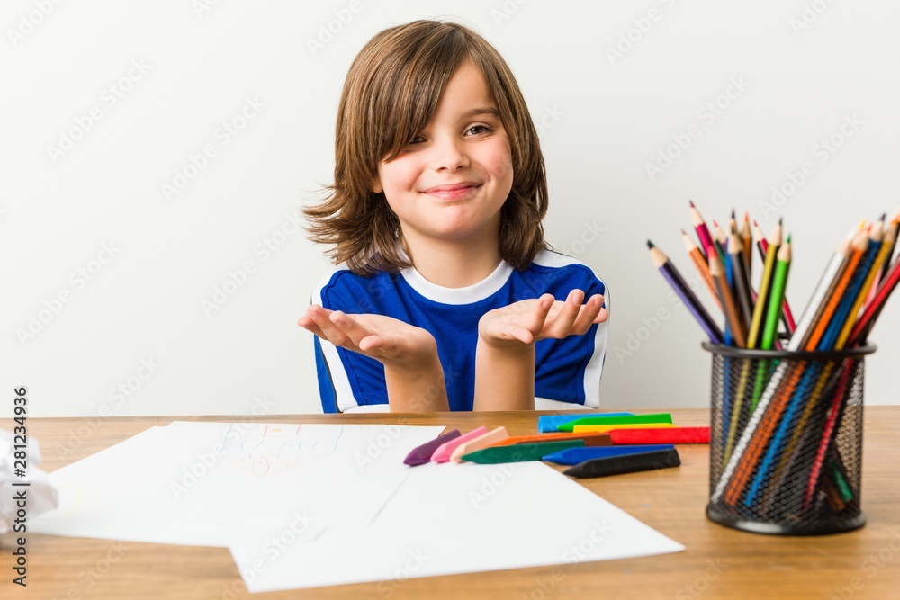Little boy painting and doing homeworks on his desk holding something with palms, offering to camera. Little boy painting and doing homeworks on his desk holding something with palms, offering to camera.