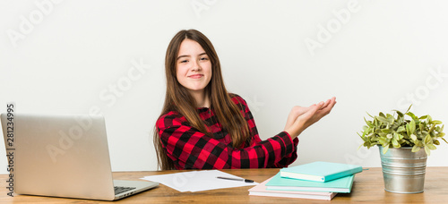 Young teenager going back to her routine doing homeworks holding a copy space on a palm.