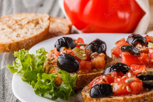 Obraz na płótnie Italian bruschetta with tomato, black olives, lettuce and mustard