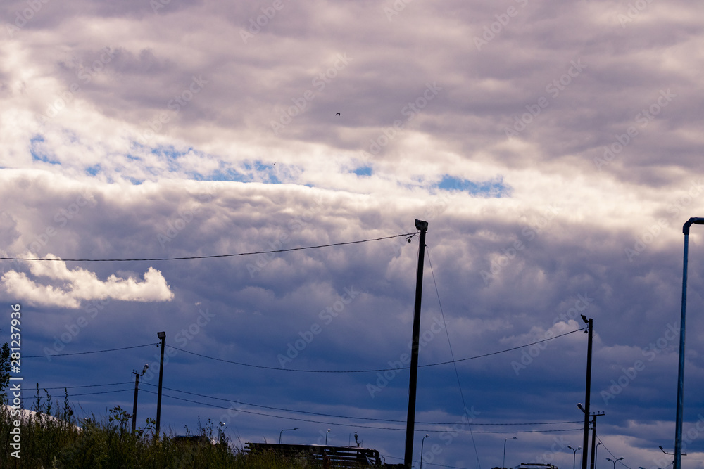 sunset over city - On a background dense clouds which were condensed over the city; On front small buildings and city lamps