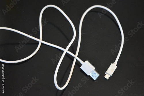 White long wire for computer and office equipment, Usb cable microusb connector on a black glossy surface.