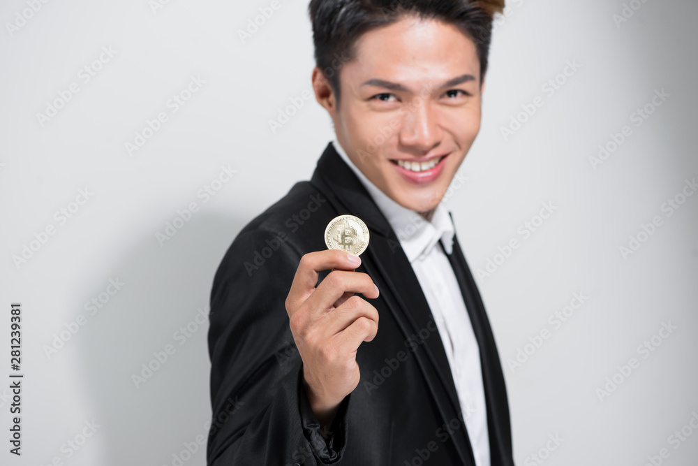 Young Asian man holding golden bitcoin with looking happy Young Asian man holding golden bitcoin with looking happy