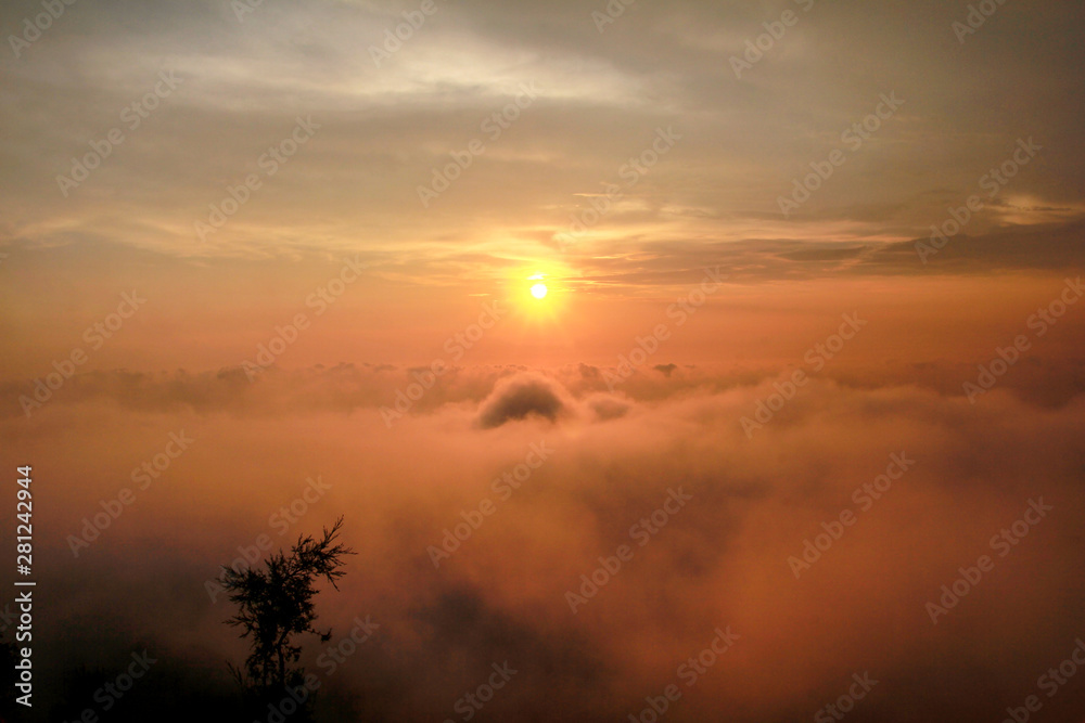 Fototapeta premium Beautiful structure of clouds on sky, mountain landscape with dense fog at sunset on horizon of beauty natural environment. Panorama of amazing sunrise view show sun rays through clouds over mountain.