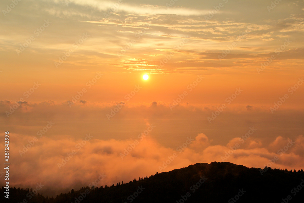 Fototapeta premium Beautiful structure of clouds on sky, mountain landscape with dense fog at sunset on horizon of beauty natural environment. Panorama of amazing sunrise view show sun rays through clouds over mountain.