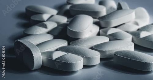 Closeup of many white prescription drugs, medicine tablets or vitamin pills in a pile - Concept of healthcare, opioids addiction, medicament abuse or medication treatment