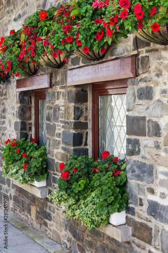 Old stone house windows with red flowers