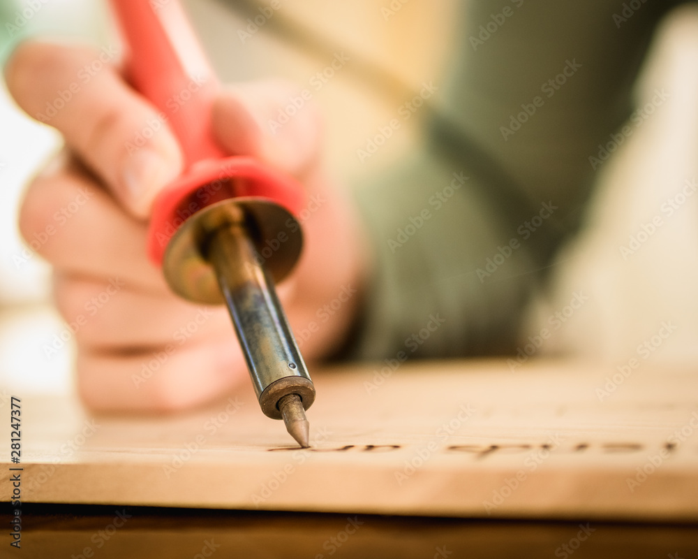 Person Holding a Wood Burning Tool, Burning Letters onto Wood Stock Photo