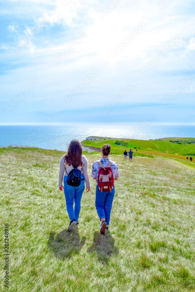 Two friends walking with an ocean background in summer at Beachy Head in Sussex, England