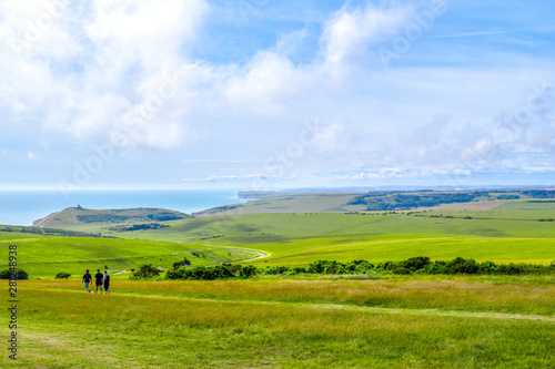 People walking through Sussex countryside with hills and the sea in summer © Ben