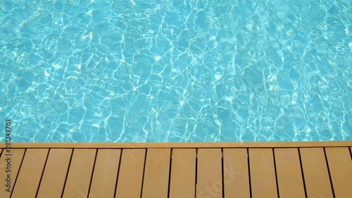 Swimming pool with wooden deck in summer time. Sport and background concept.