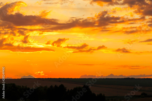 Beautiful bright majestic dramatic evening sky at sunset orange color with rays. The sun shines over the horizon against the backdrop of thunderclouds at dusk © Светлана Евграфова