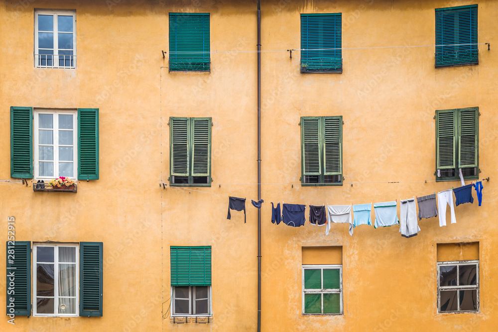 Facade of an old house with hanging washed laundry in Lucca town, in an ancient city in the Tuscany region of Italy, Europe.