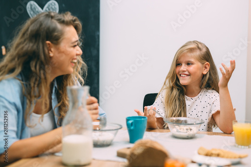 cute blonde girl having breakfast with her mother at home