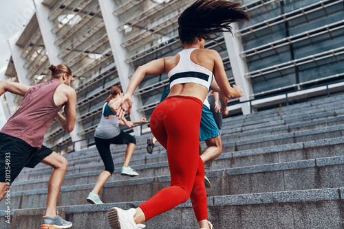 Fototapeta Naklejka Na Ścianę i Meble -  Rear view of young people in sports clothing jogging while exercising on the stairs outdoors