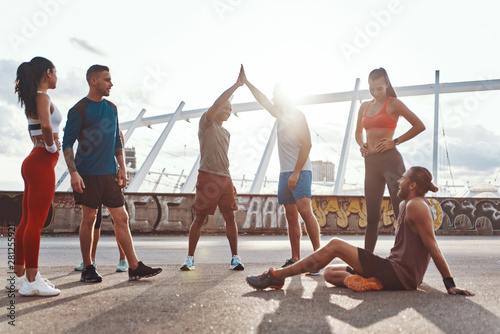 Full length of people in sports clothing encouraging each other while exercising outdoors