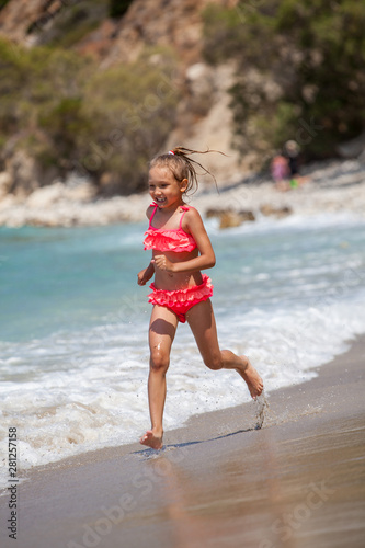 Happy child running and jumping in the waves during summer vacation on exotic tropical beach.