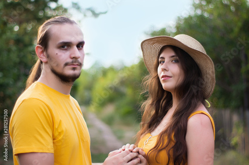 Young woman in a hat and a man on the street of the village. Portrait of a couple in love, closeup. Summer mood, hot sunny day.