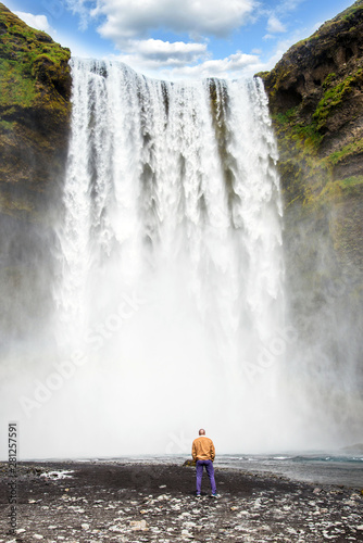 A man looks at the greatness of water jets in a waterfall Skogafoss in Iceland. Exotic countries. Amazing places.