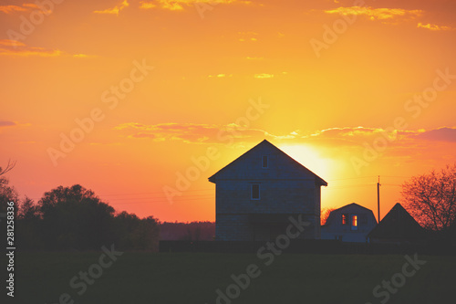 Rural landscape in the evening at sunset. Silhouette of a village against the beautiful evening sky