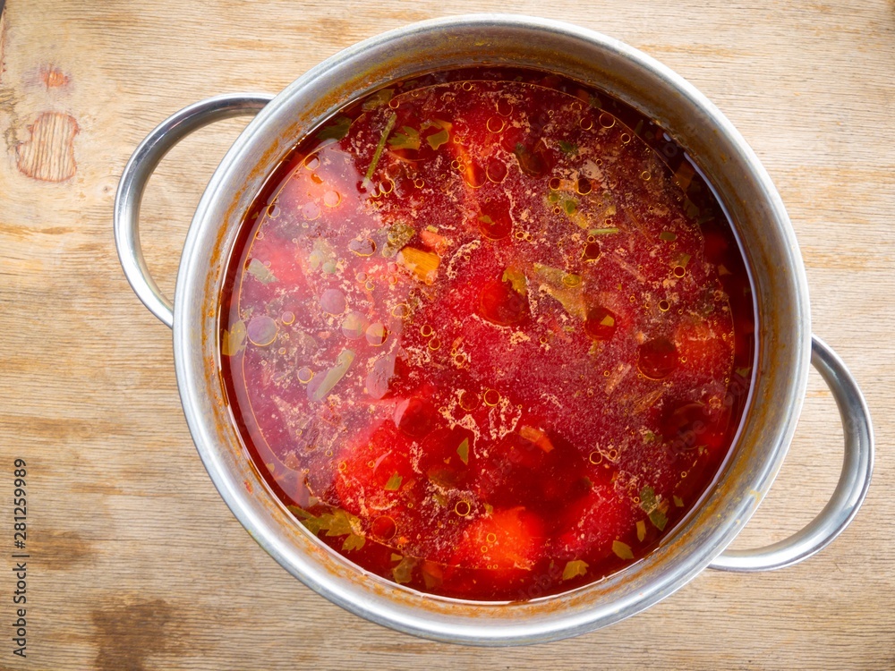 Top view on a pan full of Ukrainian borshch standing on a wooden surface