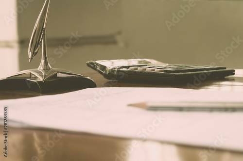 Close up of a calculator placed on office desk. A pen and a paper on the foreground. Accounting concept. Vintage background. Isolated. Shallow deapth of field. Copy space room for text. photo