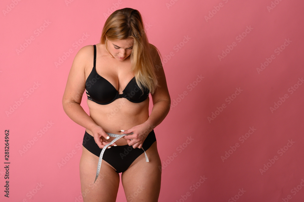 Fototapeta premium girl wearing black bikini measures the size of the waist