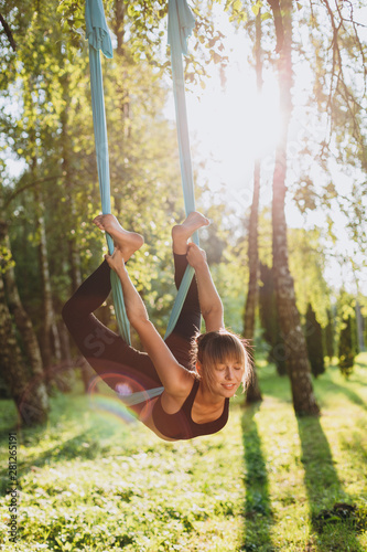 Portrait of girl doing fly yoga at the tree outdoors. - Image
