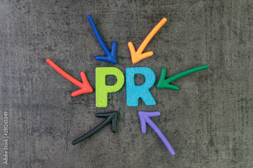 PR, Public Relation concept, multi color arrows pointing to the abbreviation PR at the center of black cement chalkboard wall, the activity to promote company