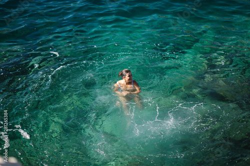 Young woman jump from the rock into the sea, water. Emotion and splash. Top view