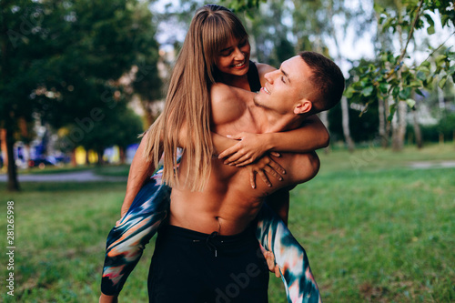 Couple man and woman have a fun time outdoor. Girl hugging a guy behind