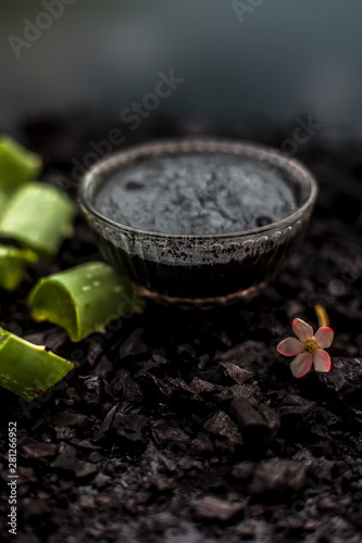 Aloe vera gel hair mask in a glass bowl consisting of activated charcoal & some aloe vera gel. To detoxify and deodorize your hair, On the wooden surface in dark colors.