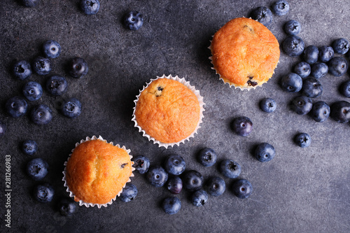 Baked muffins and fresh ripe blueberries on black background. Top view.