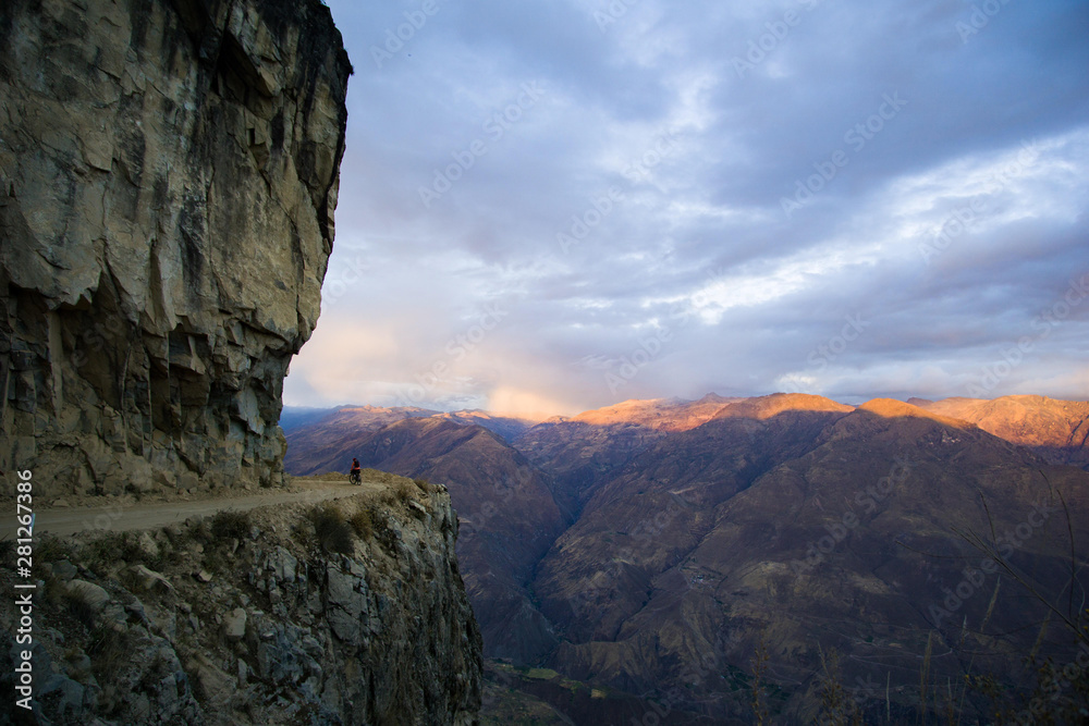 Descenso en bici sobre precipicio con la puesta de sol, Perú