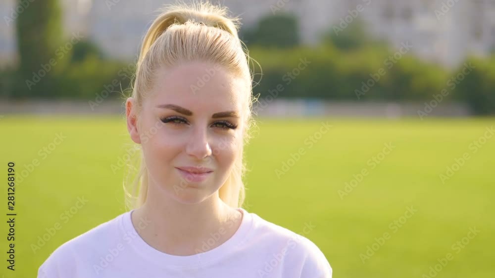 Portrait of beautiful blonde woman posing, looking at camera and smiling outdoor at garden in summer. Fashion, beauty concept. Portrait of beautiful blonde woman posing, looking at camera and smiling outdoor at garden in summer. Fashion, beauty concept.