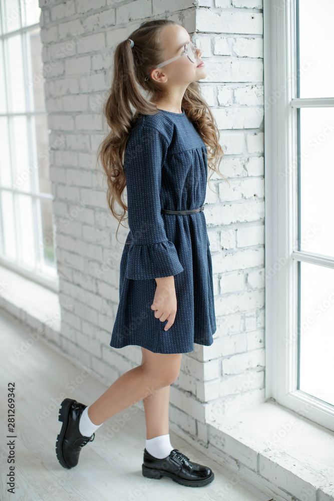 Girl schoolgirl reads a book. School fashion. Fashionable school uniform.